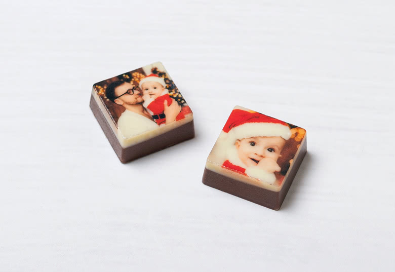 Gepersonaliseerde chocolade adventskalender vierkantjes met afgedrukte afbeeldingen van kinderen in feestelijke outfits op een witte achtergrond.
