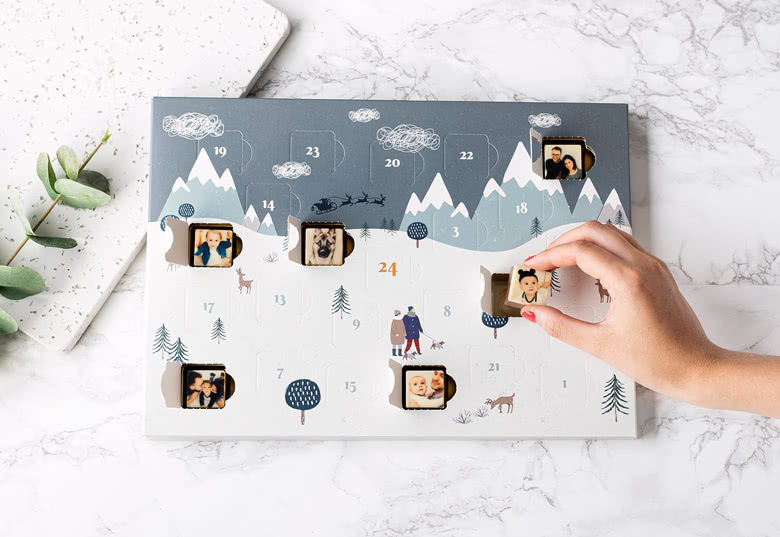 Gepersonaliseerde chocolade adventskalender met een winterbergontwerp, met fotosleuven achter genummerde deurtjes voor elke dag van december.