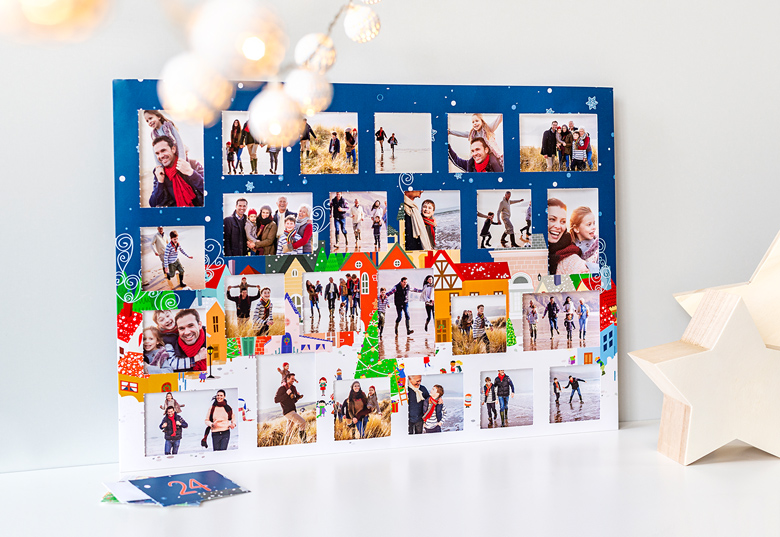 Gepersonaliseerde foto-adventskalender met een feestelijk dorpsontwerp, met genummerde deuren en aanpasbare fotovensters op een blauwe achtergrond.