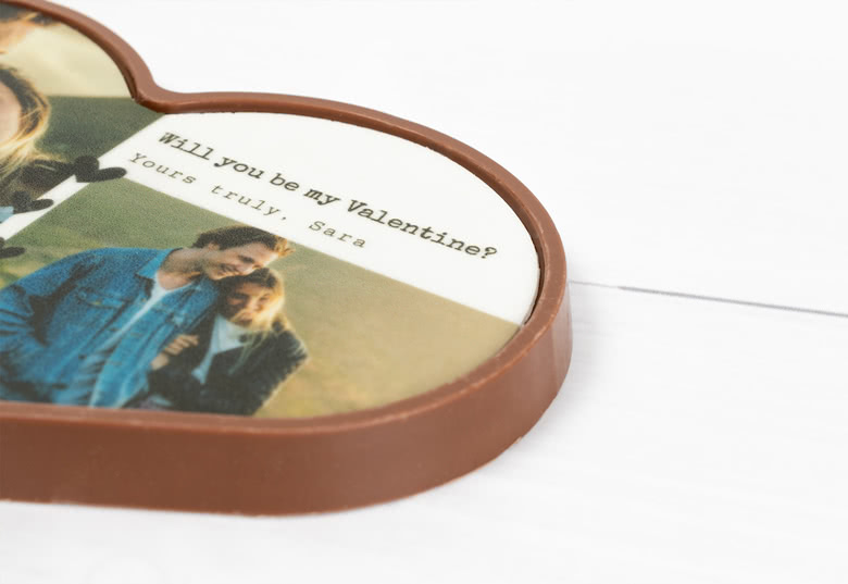 Heart-shaped chocolate with a personalised photo and message, "Will you be my Valentine? Yours truly, Sara," on a white background.