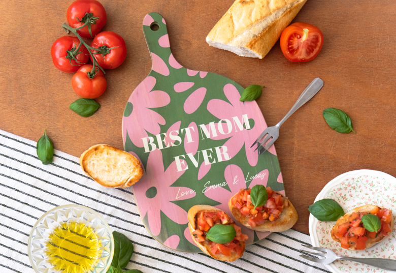 Personalised wooden cutting board with two circular photo prints, date, and names "Daniel & Olivia" in black text on a light wood background.