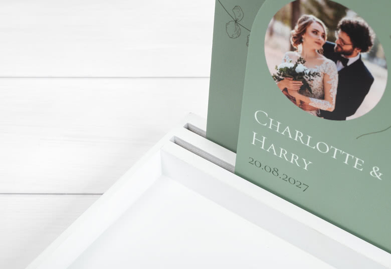 Green personalised photo favour display with names "Charlotte and Harry" and a wedding date of 20.08.2027 in white text.