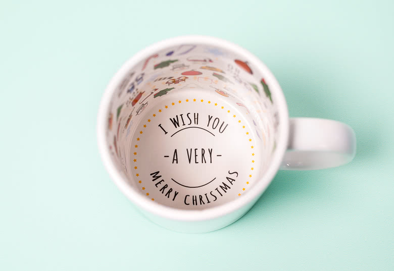 White Christmas-themed mug with festive illustrations inside and "I wish you a very merry Christmas" text at the bottom.