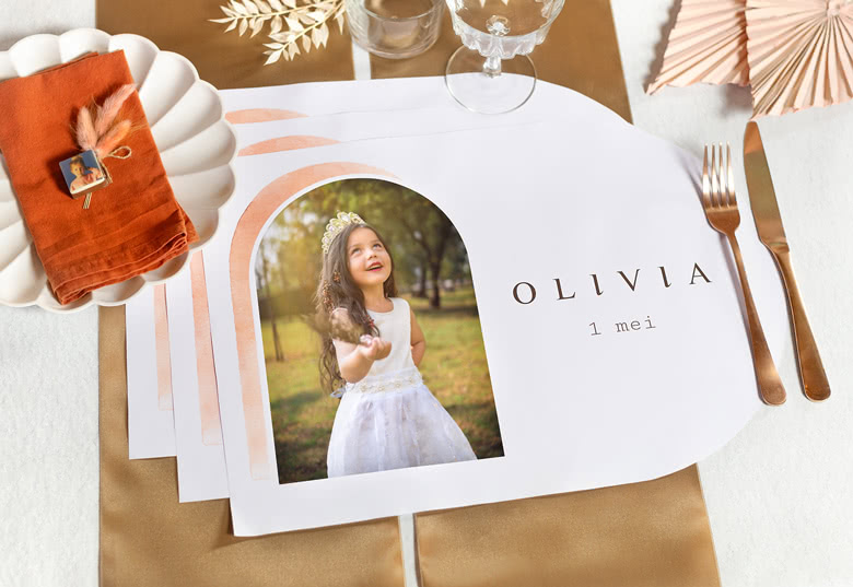 Set van gepersonaliseerde placemats met een foto van een meisje in een witte jurk, met de naam "Olivia" en datum "1 mei" erop gedrukt.