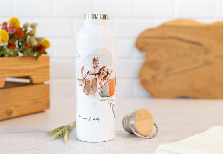 Witte thermos met een personaliseerbare foto van een moeder en kind, met de tekst "From Lang" en een zilveren dop ernaast.